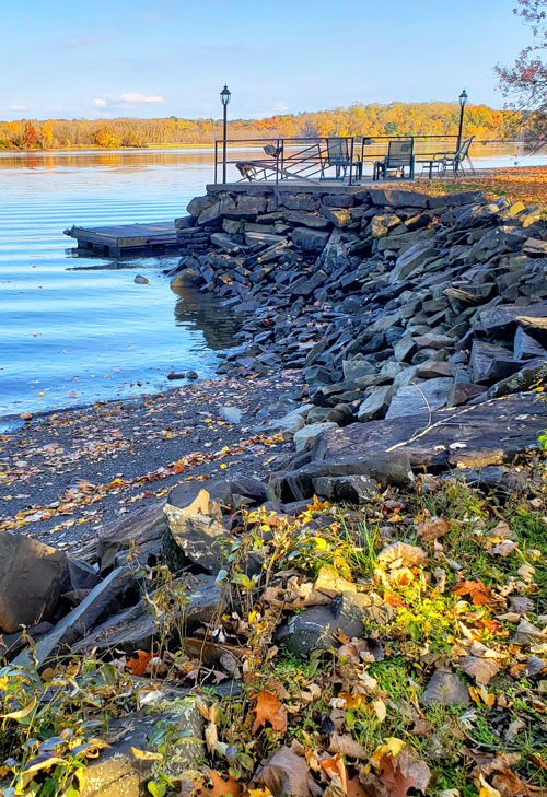 Rocky beach along river with fall colored leaves.